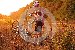 Young man repairing mountain bike in the forest