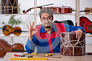 Young man repairing musical instruments at workshop