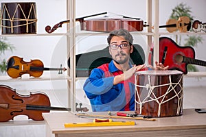 Young man repairing musical instruments at workshop