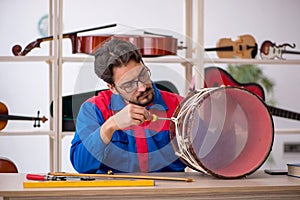 Young man repairing musical instruments at workshop