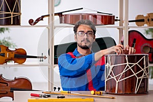 Young man repairing musical instruments at workshop