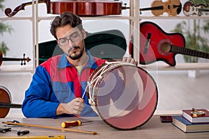 Young man repairing musical instruments at workshop