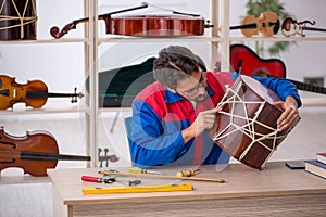 Young man repairing musical instruments at workshop