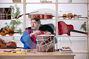 Young man repairing musical instruments at workshop