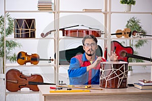 Young man repairing musical instruments at workshop