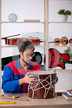 Young man repairing musical instruments at workshop