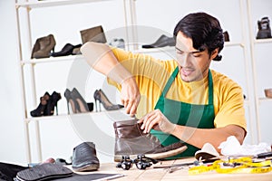 The young man repairing shoes in workshop