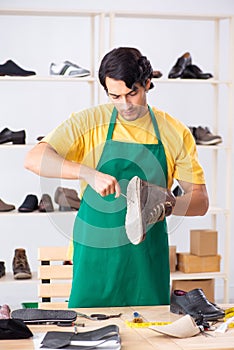 The young man repairing shoes in workshop