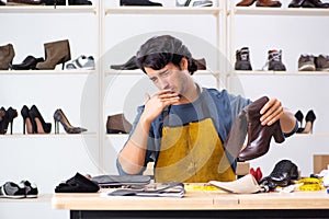 The young man repairing shoes in workshop