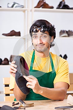 The young man repairing shoes in workshop