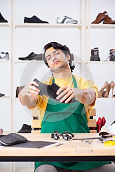 The young man repairing shoes in workshop