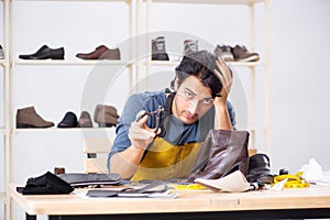 The young man repairing shoes in workshop