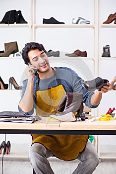 The young man repairing shoes in workshop