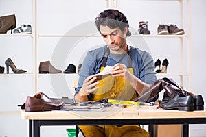 The young man repairing shoes in workshop