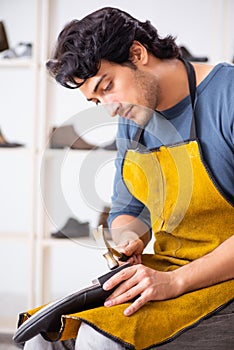 The young man repairing shoes in workshop