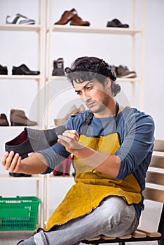 The young man repairing shoes in workshop