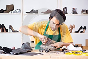 The young man repairing shoes in workshop