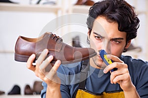 The young man repairing shoes in workshop