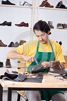 The young man repairing shoes in workshop