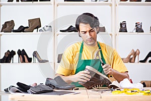 The young man repairing shoes in workshop