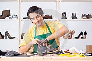 The young man repairing shoes in workshop