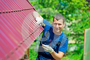 A young man repairs the roof of the house in overalls