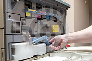 Young man replacing color toner inside a copier