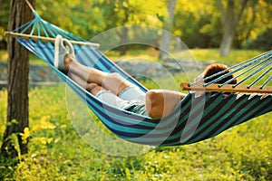 Young man resting in comfortable hammock at garden