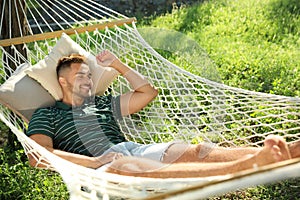 Young man resting in comfortable hammock at garden