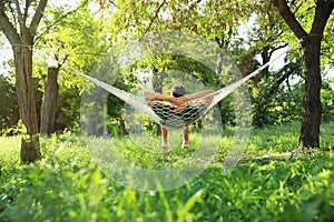 Young man resting in comfortable hammock at garden