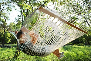 Young man resting in comfortable hammock at garden