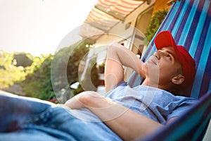 Young man resting in hammock near motorhome outdoors on sunny day