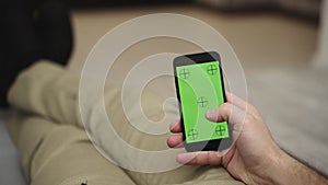 Young man resting and using mobile phone and doing swiping, scrolling gestures