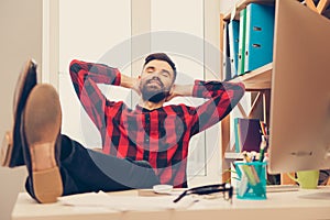 Young man resting after working day and holding legs on table