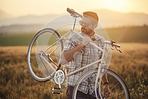 Young man with retro bicycle in sunset on the road, fashion photography on retro style with bike