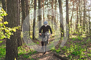 Young man ride mountain bike in forest. Young athletic man riding a bicycle in park. Male cyclist wearing face respirator, with