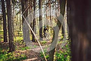 Young man ride mountain bike in forest. Young athletic man riding a bicycle in park. Male cyclist wearing face respirator, with