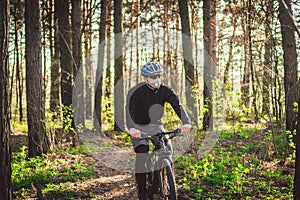 Young man ride mountain bike in forest. Young athletic man riding a bicycle in park. Male cyclist wearing face respirator, with