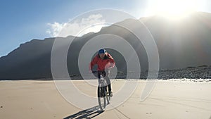 Young man rides a bicycle on a sand beach on Canary Islands. Lanzarote, Atlantic ocean.