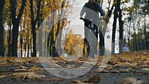 Young man riding bicycle through city park amongst colorful trees in autumn day. Sporty guy cycling outdoor. Yellow dry