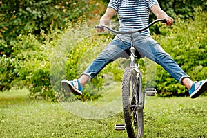 Young man riding bicycle with her legs in the air