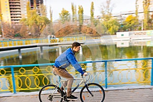 Young Man Riding Bicycle near Water in Autumn