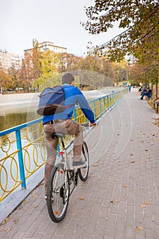 Young Man Riding Bicycle Through Park in Autumn