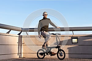 Young man riding an electric bike as a sustainable urban transportation to avoid pollution in the city.