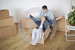 Young Man Riding His Happy Wife In Cardboard Box On Moving Day