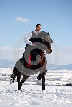 Young man riding horse outdoor in winter