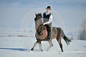 Young man riding horse outdoor in winter