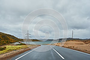 Young man riding a longboard on empty winding mountain road in summer, rear view.