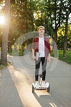 Young man riding on mini gyroboard in summer park