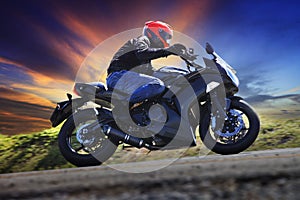 Young man riding motorcycle on curve of asphalt country road